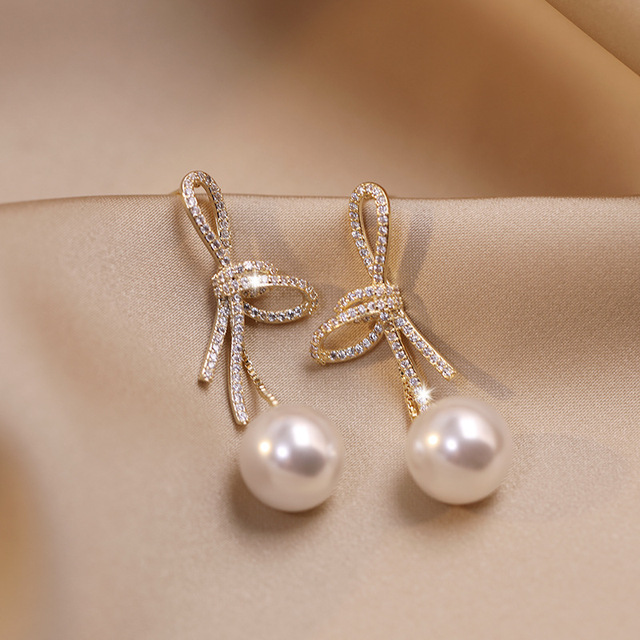 Boucles d'oreilles en perles avec un nœud brillant en or